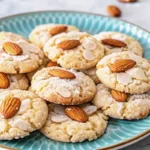 Soft and buttery almond cookies stacked on a plate