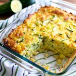 Cheesy zucchini cornbread casserole baked in a dish, golden and bubbly on top