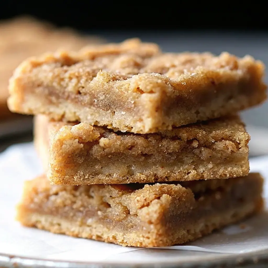 Stack of golden cinnamon sugar blondies with crackly tops on a wooden board
