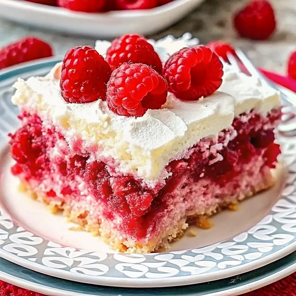 Moist Raspberry Zinger Poke Cake topped with creamy whipped layer and pink coconut