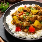 Authentic Jamaican curry chicken with rice and peas on a rustic plate