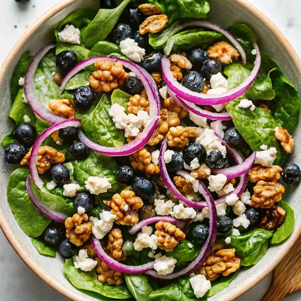 Fresh blueberry walnut salad with greens, cheese, and vinaigrette in a white bowl