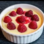 Raspberry Greek yogurt cheesecake cup topped with glossy raspberry coulis and fresh raspberries