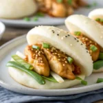 Spicy Korean chicken buns with glossy gochujang glaze in steamed bao