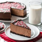 Slice of Chocolate Peppermint Cheesecake with ganache and crushed candy canes on top