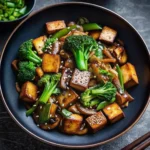 Mushroom and tofu stir-fry in a wok with vegetables and glossy sauce