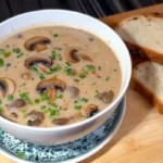 Homemade cream of mushroom soup in a bowl with fresh mushrooms and herbs