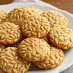 Pignoli Cookies coated in pine nuts on a baking tray
