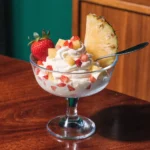 Pineapple strawberry cream cheese dessert dip in a bowl with fresh fruit and cookies for dipping