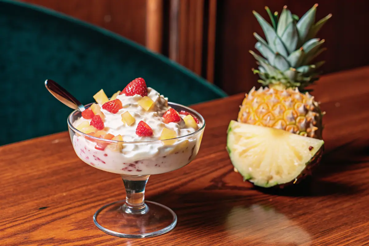 Pineapple strawberry cream cheese dessert dip in a bowl with fresh fruit and cookies for dipping