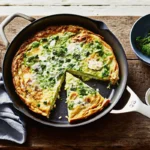 Broad Bean and Feta Frittata served in a skillet with fresh herbs and crumbled feta