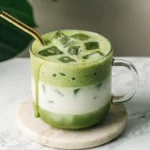 Glass of iced vanilla matcha cooler with creamy layers and ice