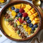Tropical mango smoothie bowl topped with fresh fruit and granola