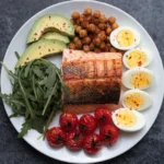 Healthy salmon power bowl with quinoa, avocado, cucumber, and vegetables