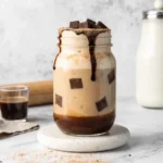 Homemade iced mocha served in a tall glass with whipped cream and chocolate drizzle