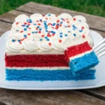 Patriotic poke cake topped with whipped cream, strawberries, and blueberries