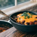 Spicy queso black bean sweet potato chili topped with melted cheese and fresh cilantro